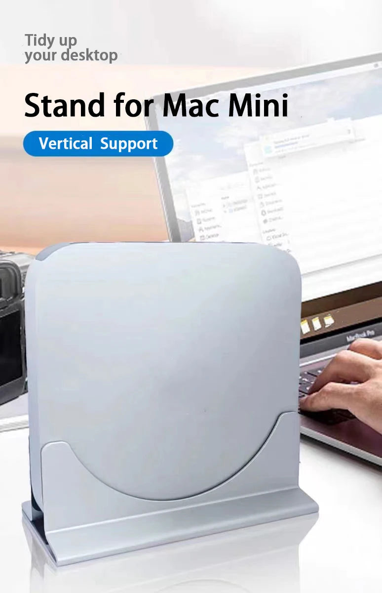 White stand for Mac Mini with text 'Tidy up your desktop' and 'Vertical Support' on a blurred background of a person using a laptop.