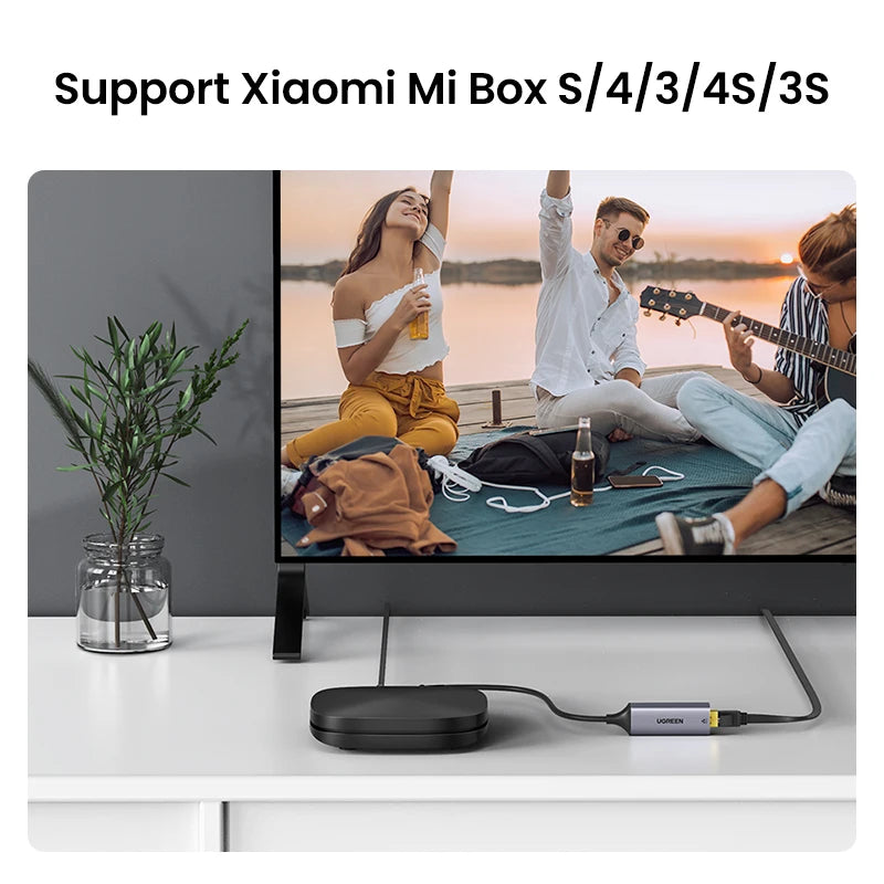 TV screen displaying a man and woman with a guitar, connected to a device labeled 'HDMI' on a white surface.