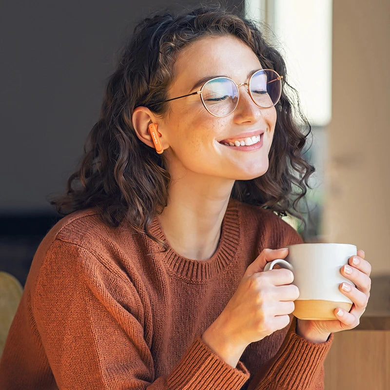 Woman wearing glasses and a brown sweater holding a white mug.
