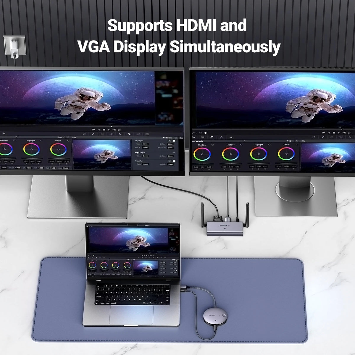 Two monitors displaying a space-themed wallpaper, connected to a laptop with a dock on a marble surface.