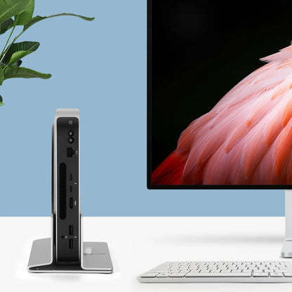 Computer setup with a monitor displaying a flamingo, a keyboard, and a small device on a white surface with a blue background.